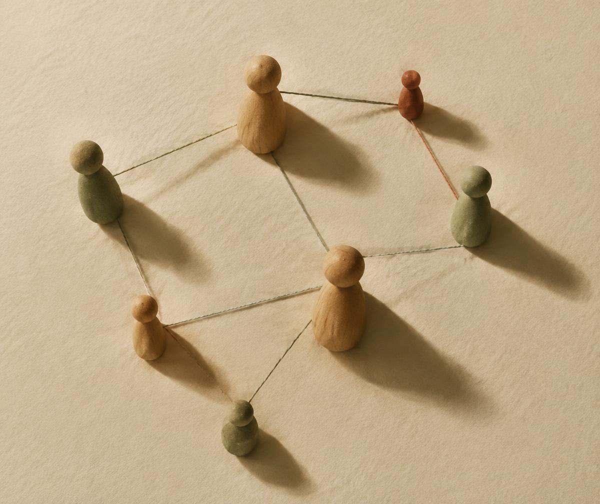 Representações de uma constelação familiar: pequenas figuras ligadas por fios sobre papel creme